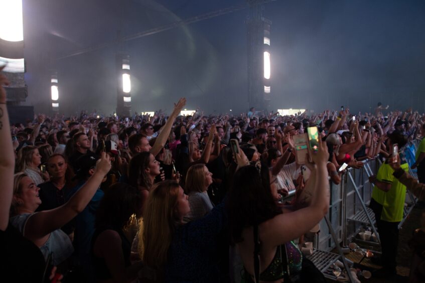 Large crowd cheering, dancing and filming with phones inside the main tent at doof in the Park 2025, Camperdown Park, Dundee.