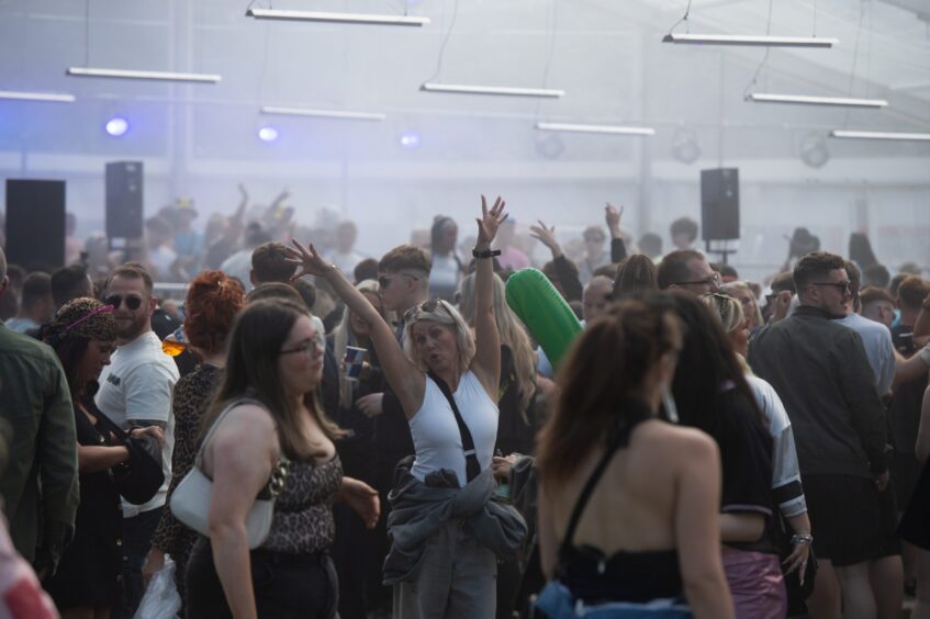 Crowd dancing under purple lights and smoke inside a festival tent at Doof in the Park 2025, Camperdown Park, Dundee.