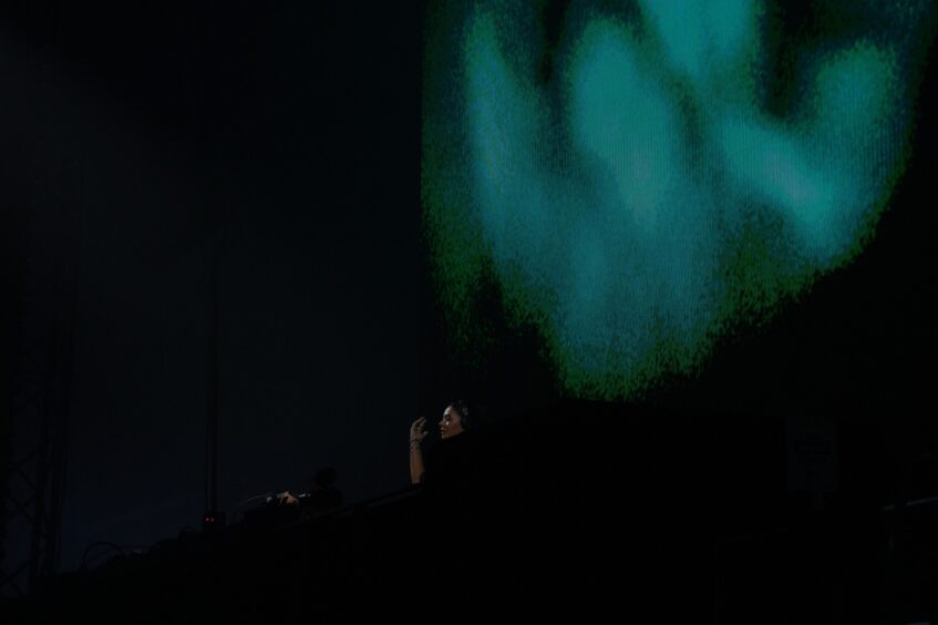 DJ Hannah Laing performs on stage with green and blue visuals during her headline set at doof in the Park 2025, Camperdown Park.