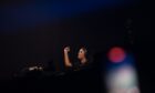 DJ Hannah Laing performing with eyes closed and hand raised on stage at Doof in the Park 2025, Camperdown Park, Dundee.