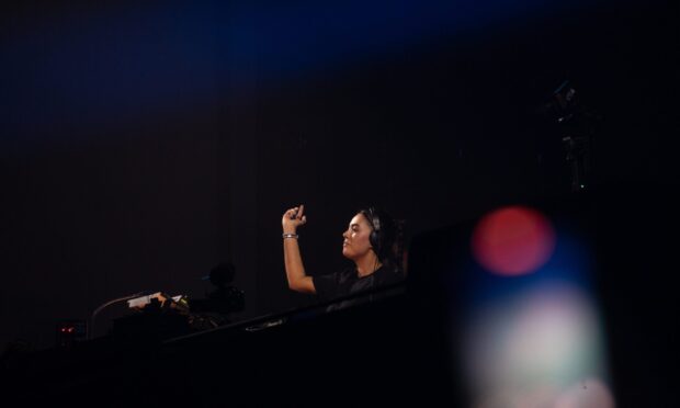 DJ Hannah Laing performing with eyes closed and hand raised on stage at Doof in the Park 2025, Camperdown Park, Dundee.
