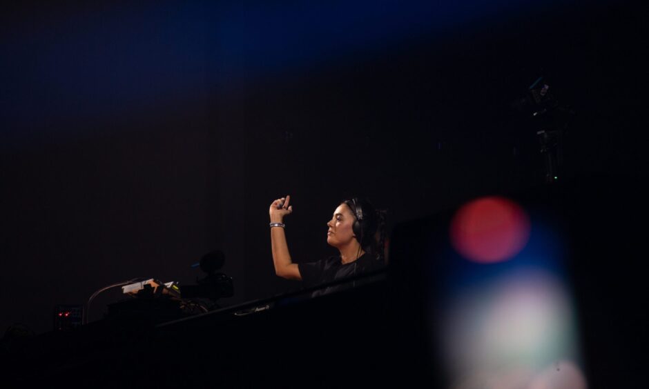 DJ Hannah Laing performing with eyes closed and hand raised on stage at Doof in the Park 2025, Camperdown Park, Dundee.