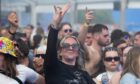 Crowd dancing and raising hands in a covered stage area during doof in the Park 2025 at Camperdown Park, Dundee.