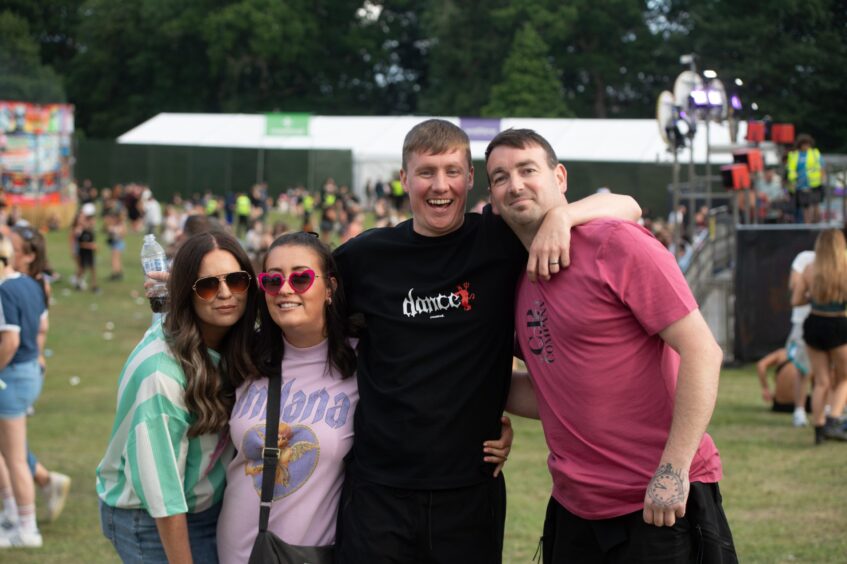 Two women and two men smiling with arms around each other at doof in the Park 2025, Camperdown Park, Dundee.
