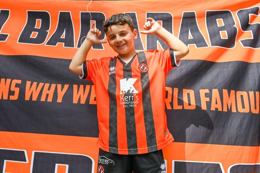 Jake Sellars poses in front of a Dundee United flag.