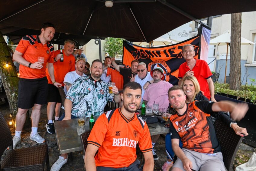 A big group of Dundee United fans smile for the camera.