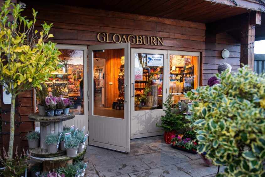 Entrance to Gloagburn farm shop with plants outside and warm lighting inside