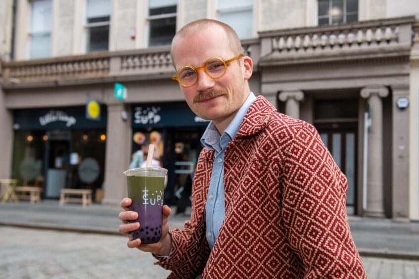Jacob Smith holding a matcha bubble tea.