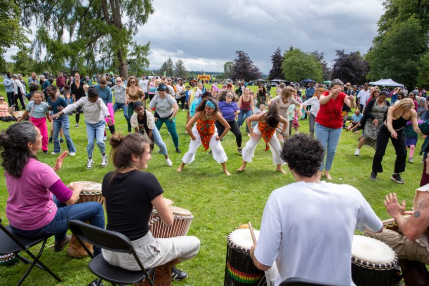 A large group of people dance in unison to live drumming in Pittencrieff Park during the Afro-Caribbean Summer Festival in Dunfermline.