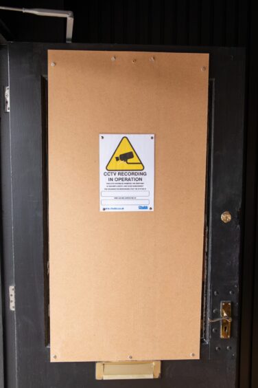 The boarded-up door warns of CCTV recordings.