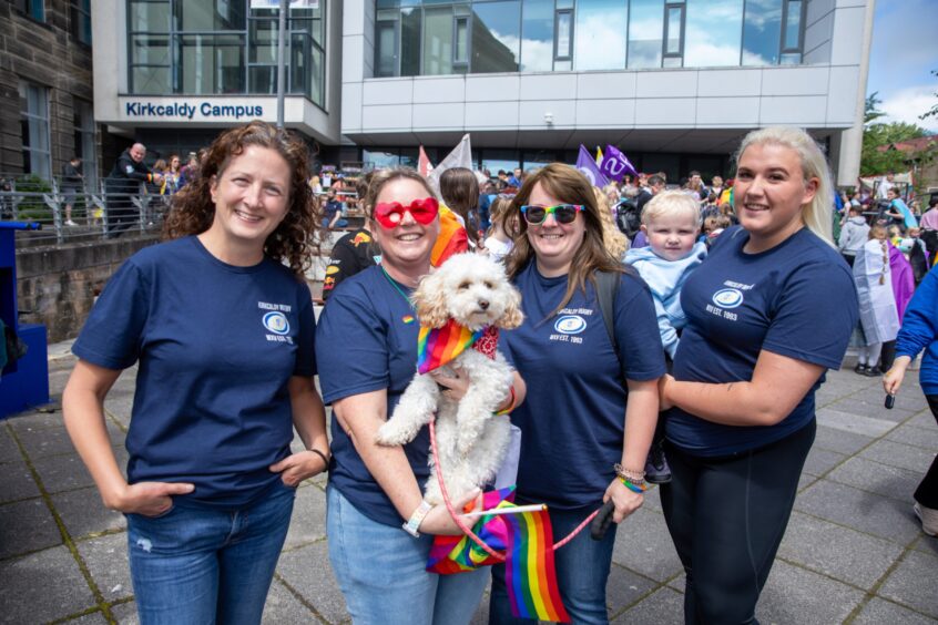 Group from Kirkcaldy Rugby Club wearing matching shirts at Fife Pride 2025, holding a rainbow-clad dog and standing outside Kirkcaldy Campus.