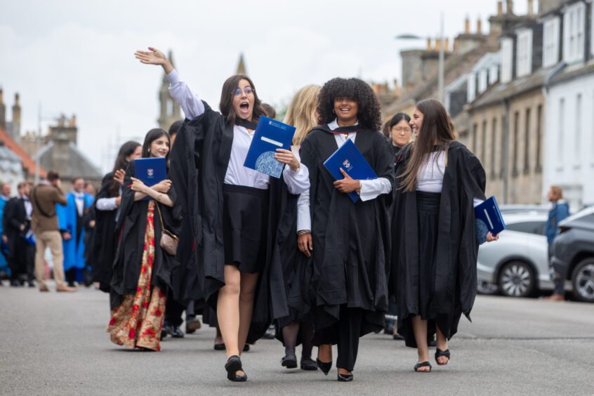 Smiles and waves from St Andrews University graduates.