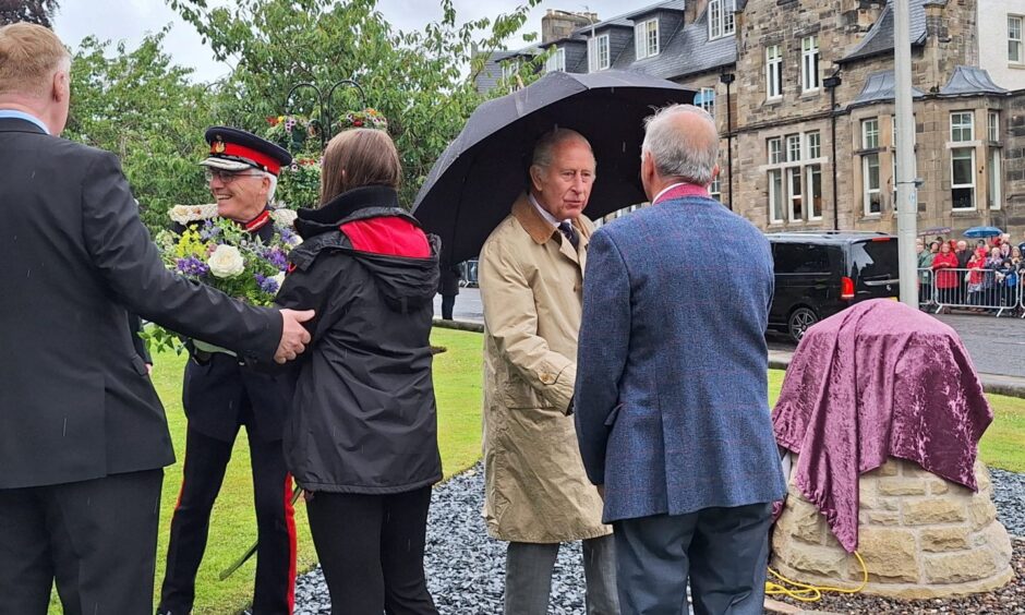 King Charles shakes hands with stone mason George Sweeney, who made the memorial cairn