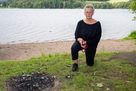 |Emily Crichton kneeling beside remains of bonfire next to Loch of Clunie