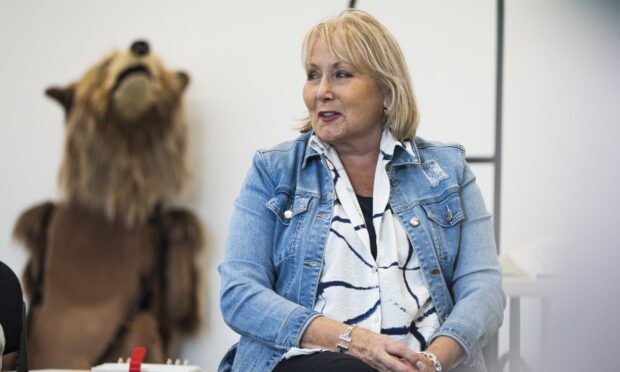 Former Hercules the Bear owner Maggie Robin sitting down with a bear puppet in the background.