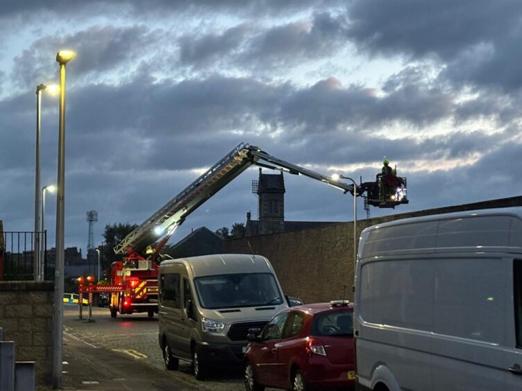 A firefighter mans a height appliance amid a fire at Caldrum Works in Dundee.
