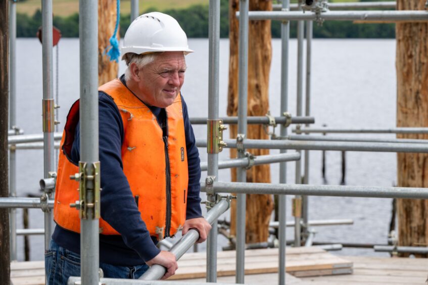 Mike Benson in hard hat and orange hi-vis jacket on scaffolding at crannog construction