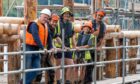 Five people standing on scaffolding beside Scottish Crannog Centre