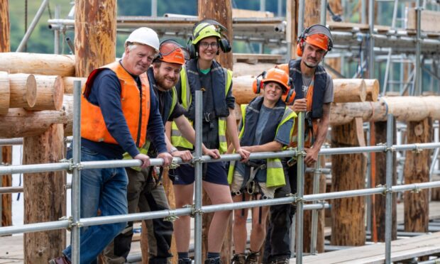 Five people standing on scaffolding beside Scottish Crannog Centre