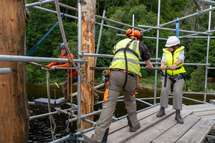 People turning device that is pushing timber strut into loch bed