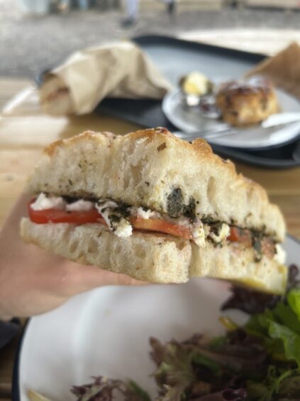 A focaccia sandwich stuffed with vegan mozzarella, sliced tomatoes and pesto.