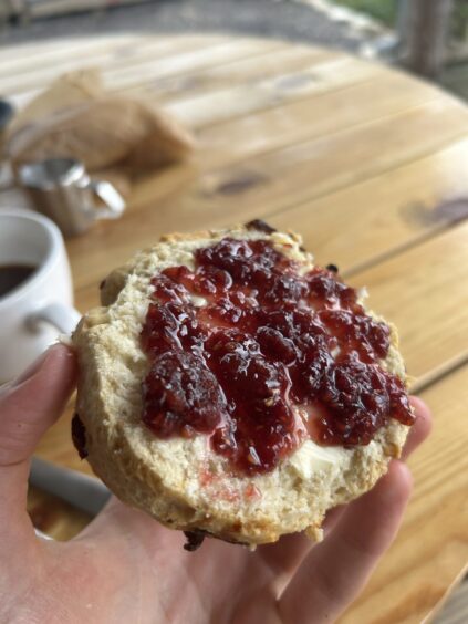 A halved scone, covered in jam.