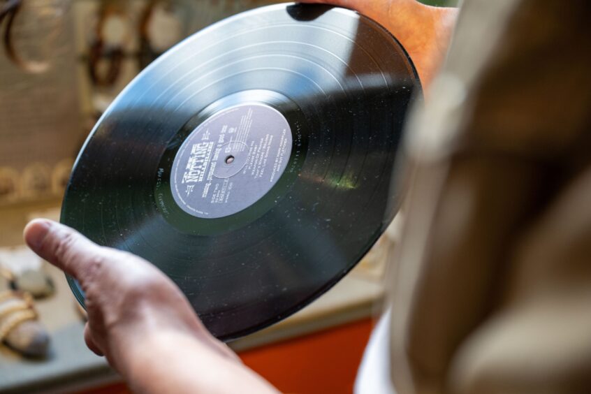 Hand holding vinyl record above turntable