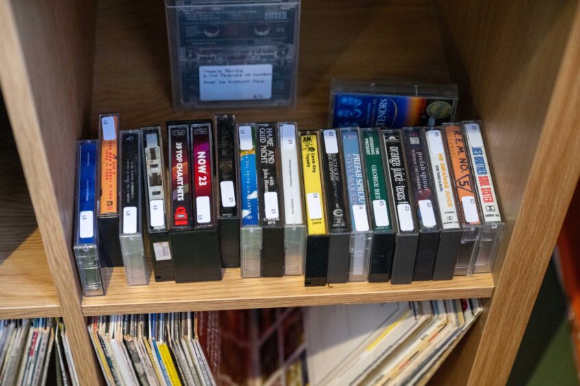 Row of cassette tapes on shelf. from artists such as REM and Orange Juice