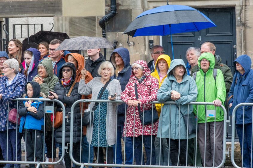 People with umbrellas and hoods up watch the royal proceedings in Kirkcaldy