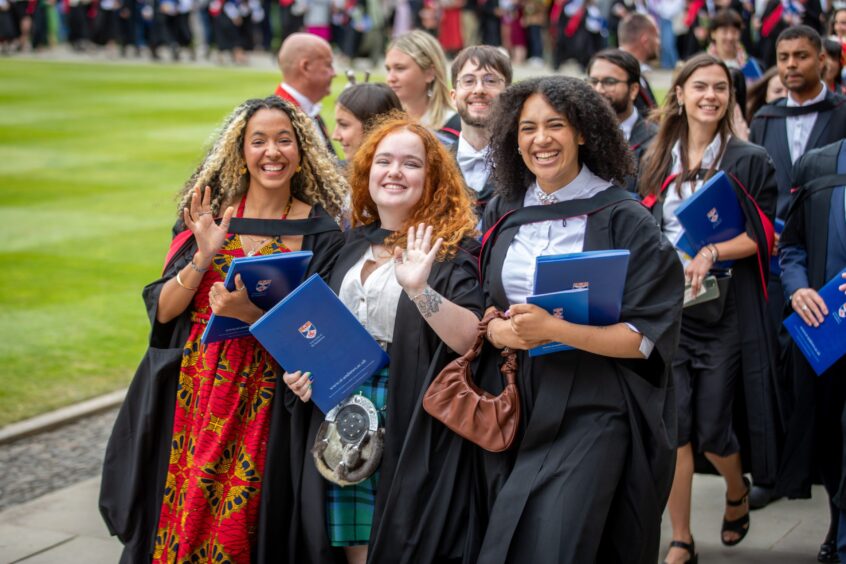 Big smiles and waves from graduates.