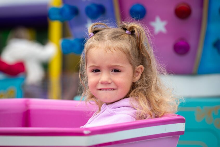 A young girl enjoying the Tea Cups ride at St Andrews Highland Games.