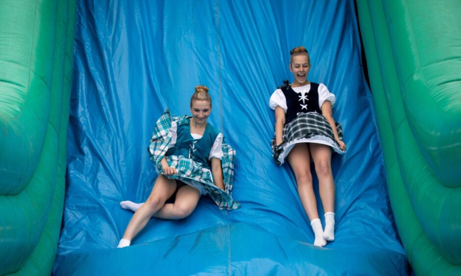 Highland Dancers enjoy the inflatable slide at St Andrews Highland Games.