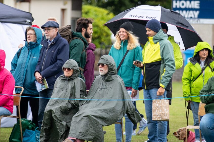 Onlookers at St Andrews Highland Games shelter from the rain.