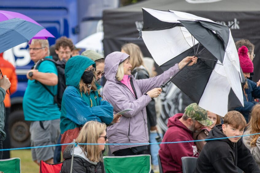 Attendees at St Andrews Highland Games turn to the umbrellas during the rain.