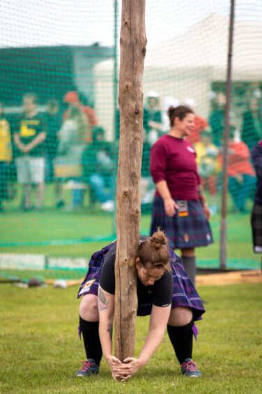 A woman gets into position to toss the caber at St Andrews Highland Games.