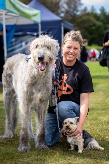 A woman attending St Andrews Highland Games with her two dogs.