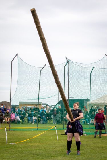 An athlete in the ladies division tossing the caber at St Andrews Highland Games.