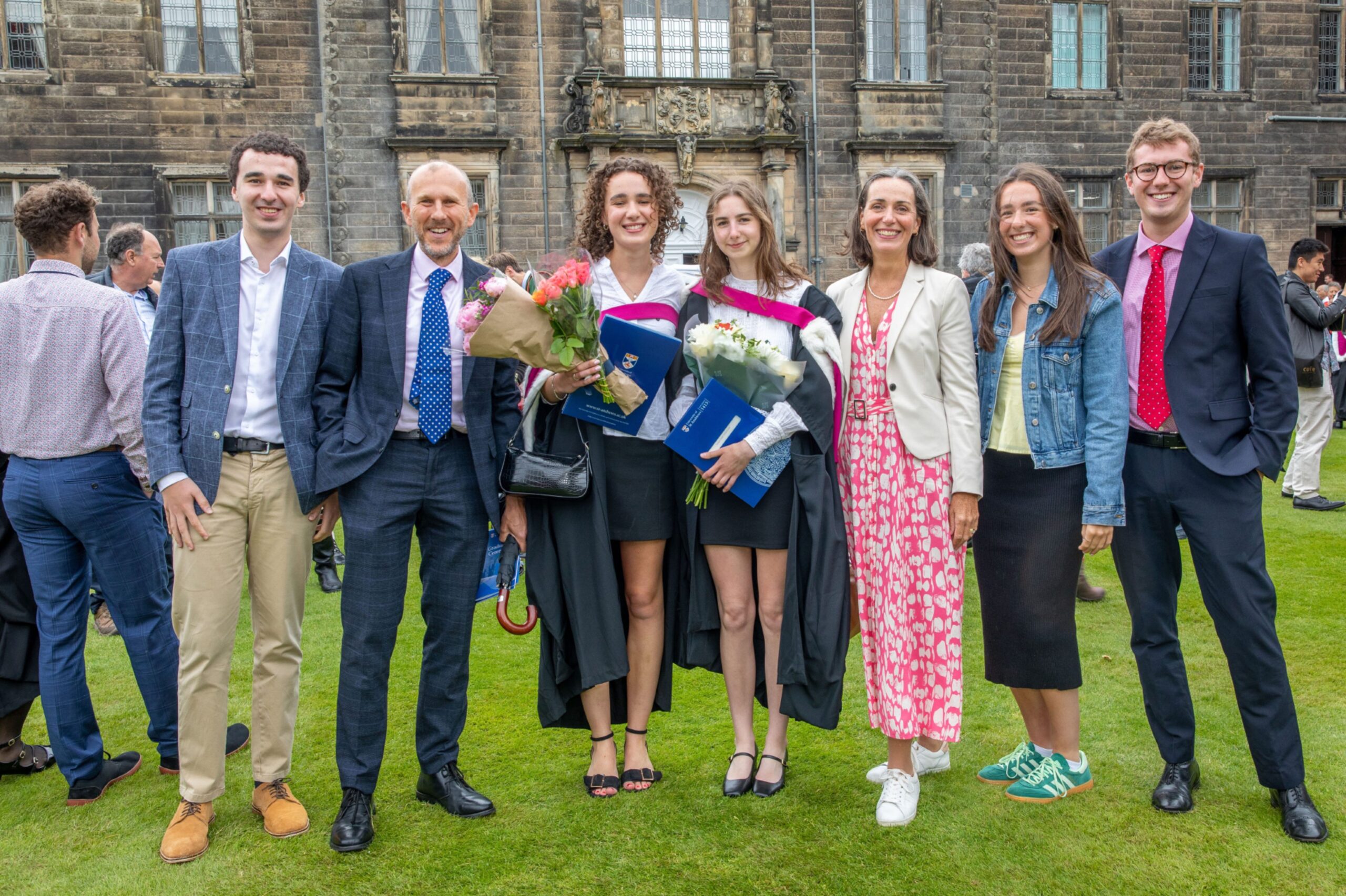 Lucy Forshaw and Isabel Fenmore with their families in St Salvator’s Quad, smiling with bouquets and certificates after graduating.