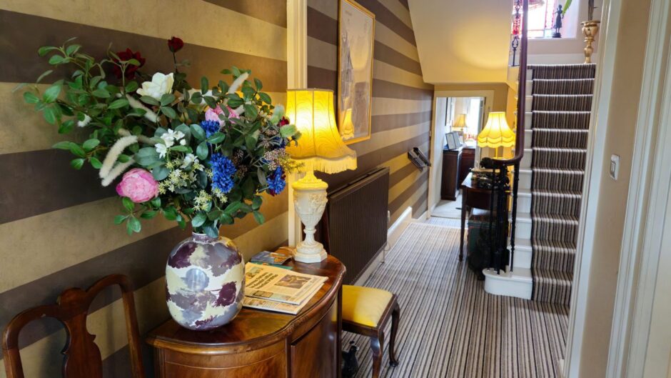 Entrance to The Townhouse with bouquet of flowers on polished cabinet and warm coloured walls