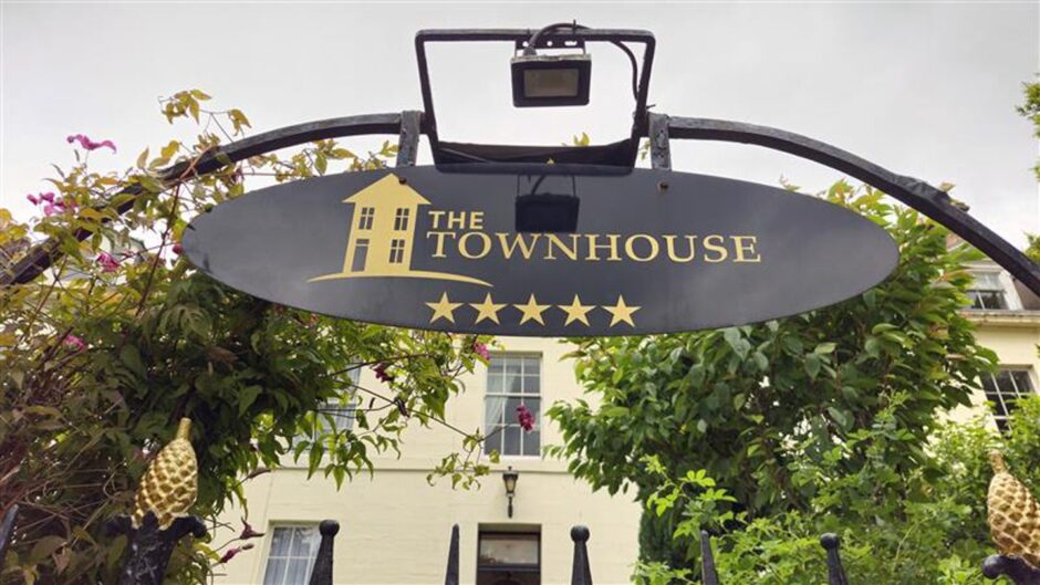 Black entrance sign outside The Townhouse, with white Georgian building behind