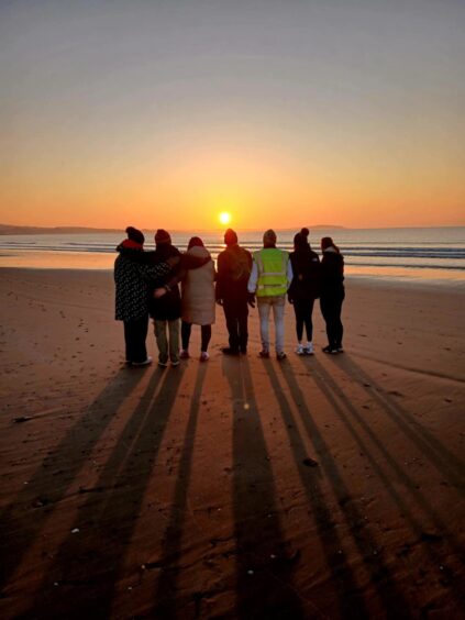 Walkers enjoying a special moment as the sun rises on Leven beach.