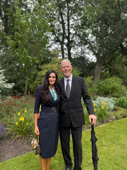 Charlie and Alastair Taylor in front of flower bed at palace
