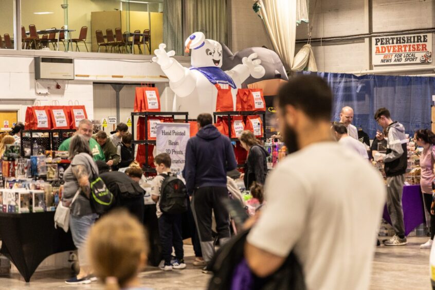 People inspecting stalls at Perth Comic Con 2025.