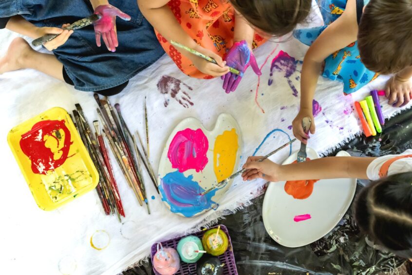 Image shows children getting messy with paint and a paint palette for some summer fun.