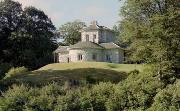 Old fashioned white building on slight slope surrounded by trees