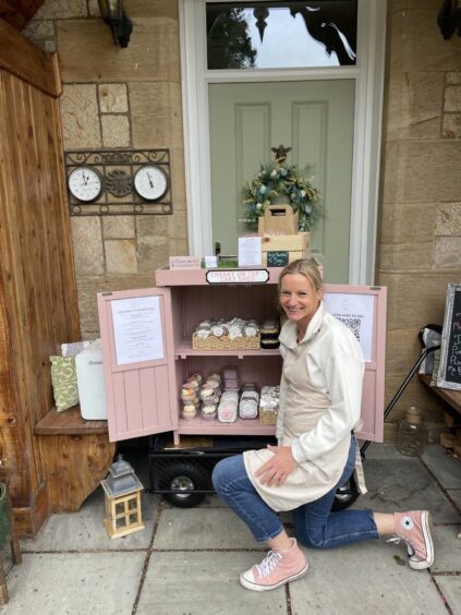 Claire Sara, kneeling by her cake shed.