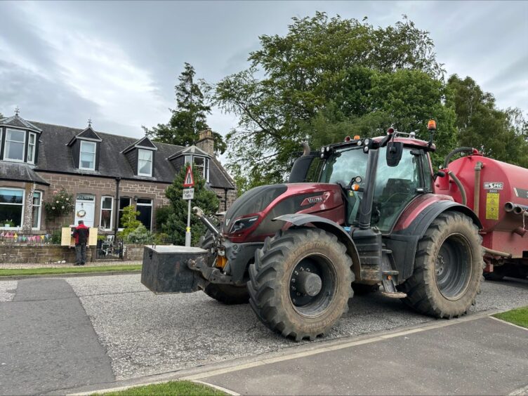 A tractor and trailer parked by the side of a road.