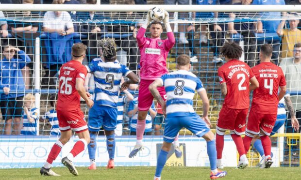 Dunfermline goalkeeper Mason Munn rises in a crowded penalty box to clutch a high ball.