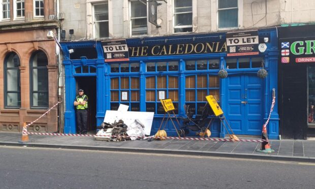 Police standing guard outside the block of flats on High Street, Perth, after the fire
