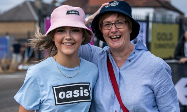 Emily McCleary and her mother Siobhan, smiling in bucket hats and Oasis-themed clothing, outside Murrayfield Stadium before the second Oasis Live ’25 concert.